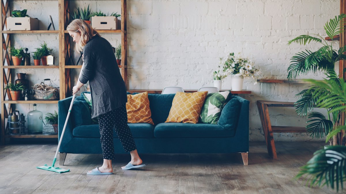 House cleaner mopping the floor of a bright, tidy living room